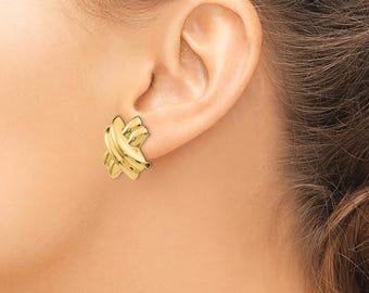 Puede incluir: Pendientes de nudo en tono dorado. Los pendientes están hechos de un metal liso y brillante y tienen un diseño simple y elegante.