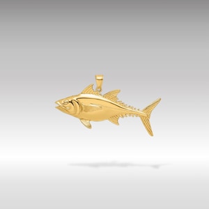 May include: A gold-colored tuna fish pendant charm. The pendant is detailed with realistic features and a textured surface.