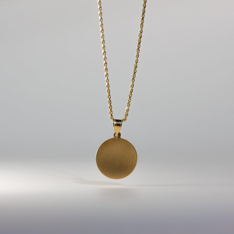 May include: A gold chain necklace with a round, brushed gold pendant.