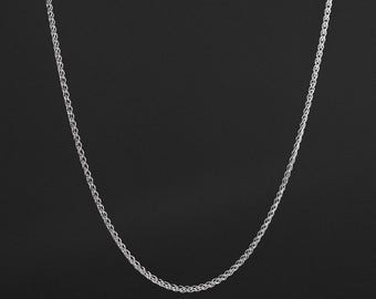 May include: A silver-toned wheat chain necklace featuring a continuous, intricate braided link pattern. The metallic chain displays a uniform, polished texture throughout its length, forming a smooth, symmetrical curve against the dark background.