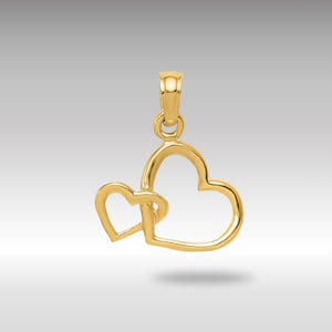 Puede incluir: Un colgante de oro con dos corazones entrelazados. Los corazones están abiertos y conectados en la parte superior, creando un diseño delicado y romántico.