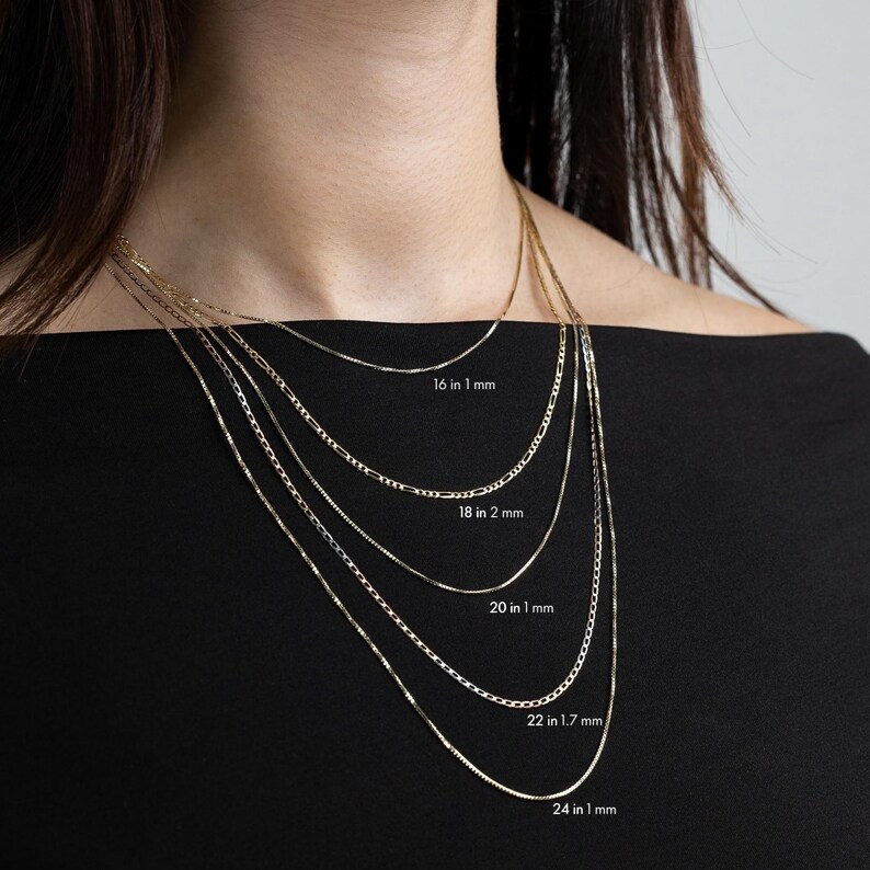 May include: Five gold chains of different lengths and widths, layered on a model's neck. The chains are labeled with their length and width in inches and millimeters: 16 in 1 mm, 18 in 2 mm, 20 in 1 mm, 22 in 1.7 mm, and 24 in 1 mm.