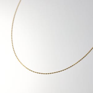 May include: A gold chain necklace with a delicate, box chain design.