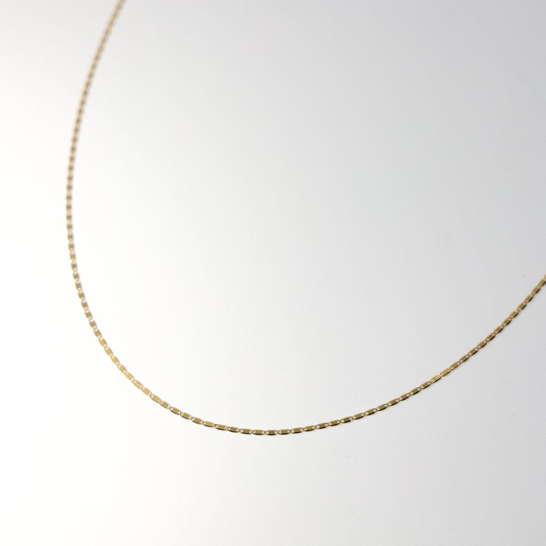May include: A gold chain necklace with a delicate, box chain design.