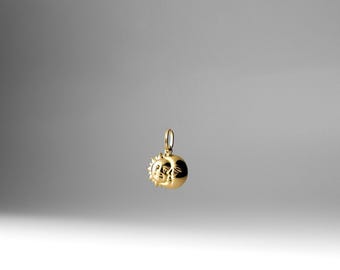 May include: A gold charm pendant featuring a sun and moon design. The sun has a face and rays, while the moon is a crescent shape.