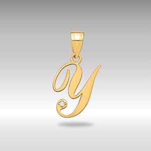 May include: A gold-colored pendant in the shape of the letter "Y" in a cursive script. The pendant has a small diamond accent and a loop for a chain. The background is a gradient of light gray.