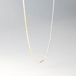 May include: A gold and silver chain necklace with a box chain design. The chain is made of metal and has a lobster clasp closure.