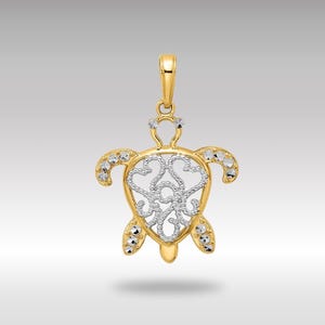 May include: A gold and silver two-tone pendant featuring a detailed filigree turtle design. The turtle's shell is openwork and the pendant is accented with small, clear stones.