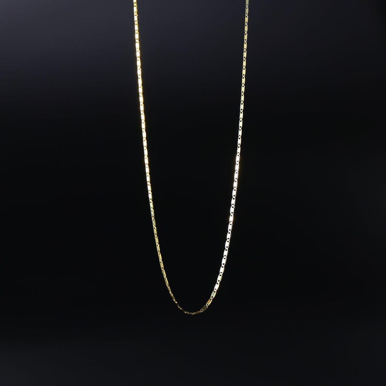 May include: A gold chain necklace with a box chain design.