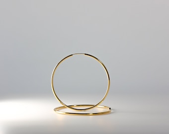 Puede incluir: Un par de pendientes de aro de oro. Los pendientes son simples y elegantes, y serían una gran adición a cualquier colección de joyas.