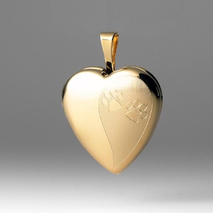 Könnte beinhalten: Ein goldener herzförmiger Anhänger mit Pfotenabdruck-Design.