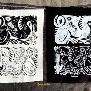May include: Two fabric patches with dragon illustrations. One patch features a black dragon on a white background, and the other has a white dragon on a black background. The dragon design includes wings, a star, and flames. The text "houndsaint" is at the bottom.