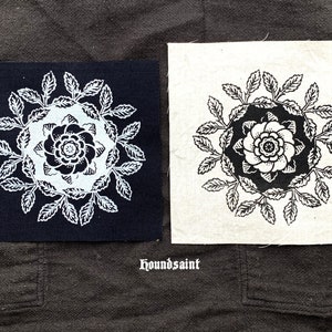 May include: Two square fabric patches with floral designs. One patch is navy blue with a white floral design, and the other is off-white with a black floral design. The text "houndsaint" is below the patches.