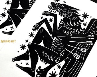 May include: Two black and white art prints featuring a wolf-like figure with human legs, surrounded by stars. One print has the text "houndsaint" in gold. The other print has the text "LEAP-EATER". The prints are on white paper.