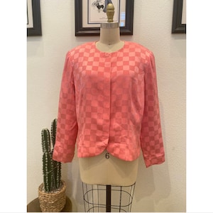 May include: A pink checkered blazer with a button closure. The blazer has long sleeves and a cropped fit.