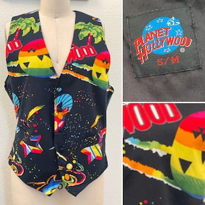 May include: A black vest with a colorful, abstract print featuring palm trees, stars, and the words "Planet Hollywood". The vest has a button closure and a size tag that reads "S/M".