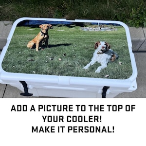 May include: A white cooler with a custom printed lid featuring two dogs, one brown and one white, on a grassy background. The text "ADD A PICTURE TO THE TOP OF YOUR COOLER! MAKE IT PERSONAL!" is printed below the cooler.