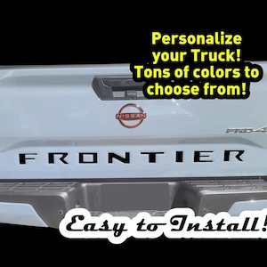 May include: A light blue pickup truck with a black "FRONTIER" tailgate decal. The truck has a Nissan emblem and a "Pro-4X" badge. The text "Personalize your Truck! Tons of colors to choose from!" and "Easy to Install!" are written in yellow and black text.