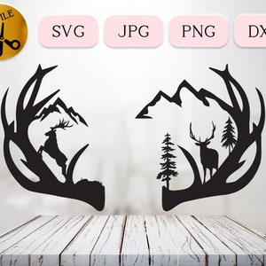 May include: Black silhouette of a deer's antlers with a mountain range and a deer inside the antlers. The antlers are on a white background.