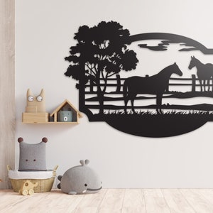 May include: Black metal wall art featuring two horses in a pasture with a tree and fence. The artwork is cut in a silhouette style, with a curved border. The background is a light-colored wall.