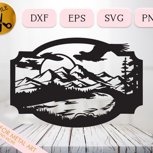 May include: Black and white silhouette of a mountain range with a lake, trees, and a bird flying overhead. The design is framed in a decorative border.