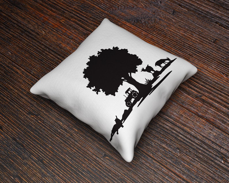 Peut inclure: Un coussin blanc avec un motif en silhouette noire d'un arbre, d'un tracteur et de cerfs.