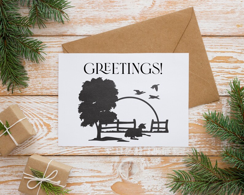 Peut inclure: Une carte blanche avec le mot "GREETINGS!" imprim&eacute; en noir. La carte pr&eacute;sente une silhouette noire d'un arbre, d'une cl&ocirc;ture, d'un oiseau et d'un petit animal. La carte est pos&eacute;e sur une surface en bois avec une enveloppe brune derri&egrave;re elle.