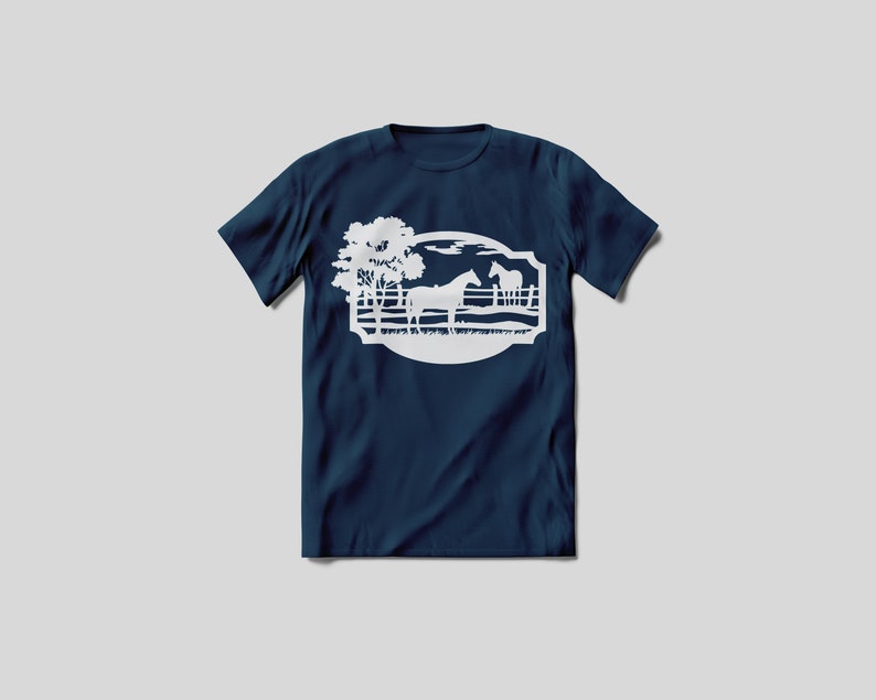 May include: Navy blue t-shirt featuring a white graphic of a horse scene. The design includes a horse, trees, and a fence within an oval frame. The shirt is made of a soft material and has short sleeves.