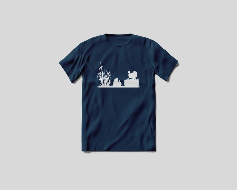 Op de afbeelding: Een marineblauw t-shirt met een wit silhouet van een kalkoen, ma&iuml;sstengels en een hooibaal.
