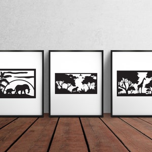May include: Three black and white framed prints featuring silhouette images of African wildlife. The first print depicts an elephant and a baby elephant walking through a savanna landscape. The second print depicts a lion and a zebra walking through a savanna landscape. The third print depicts a giraffe standing in a savanna landscape.