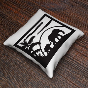 May include: White cushion with a black silhouette of two elephants walking through a jungle scene with palm trees. The elephants are walking towards a setting sun.