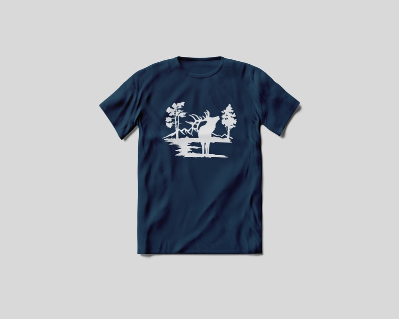May include: A navy blue t-shirt with a white silhouette of an elk standing in a lake with trees on either side.