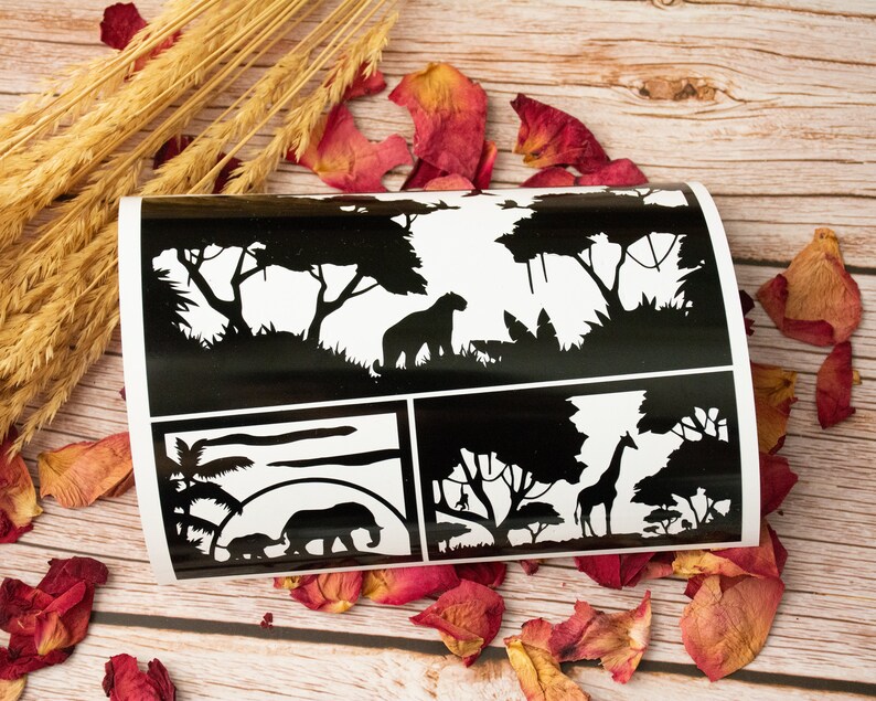 May include: Black and white stencil sheet featuring four different designs. The designs include a lion, a giraffe, an elephant, and a sunset scene. The stencil sheet is ideal for crafting and DIY projects.