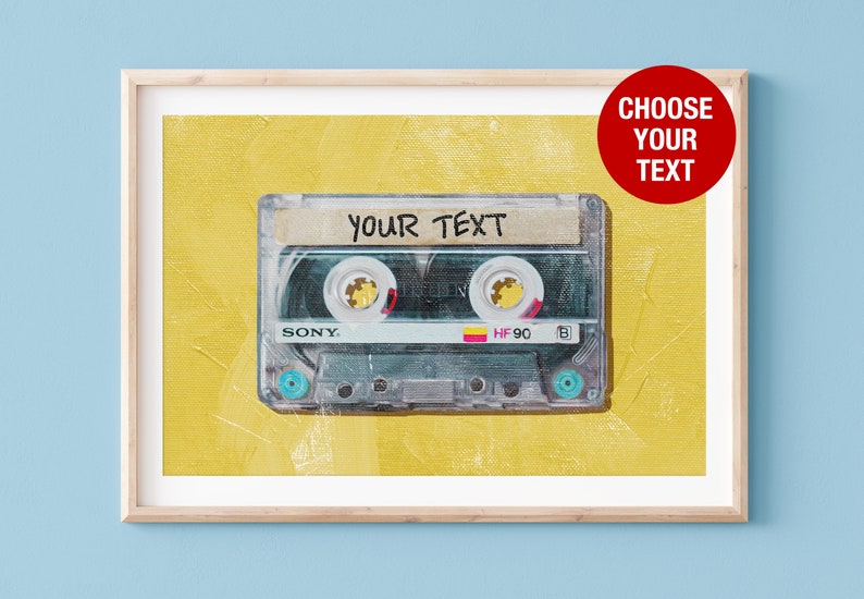 以下が含まれることがあります： 黄色の背景に、ビンテージスタイルのカセットテープ。テープには「YOUR TEXT」という文字がラベルに書かれています。テープは木製のフレームに入っています。