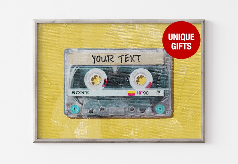 以下が含まれることがあります： 黄色の背景に、ビンテージのカセットテープ。テープには「YOUR TEXT」と書かれています。テープは銀色のフレームに入っています。
