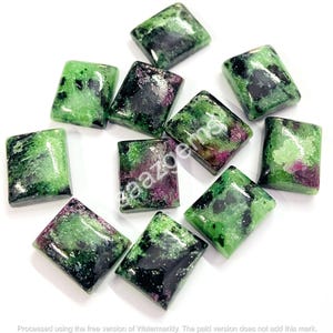 May include: A collection of rectangular gemstones with a mix of green, black, and red hues. The stones are polished and have a glossy finish. The gemstones are arranged on a white surface.