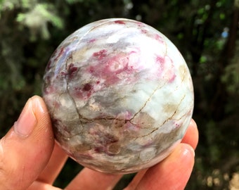May include: A polished sphere of green, white, and pink crystal with a swirling pattern. The sphere is smooth and has a glossy finish.