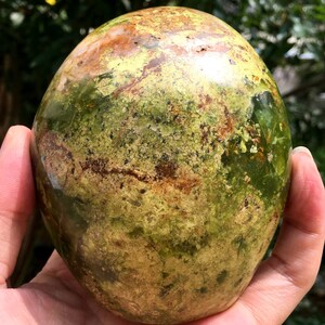 May include: A polished green and brown opal sphere with a mottled pattern.