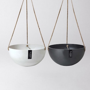 May include: Two hanging planters, one white and one black, with a rope hanging system. Both planters have a label that says "KANSO" on them.