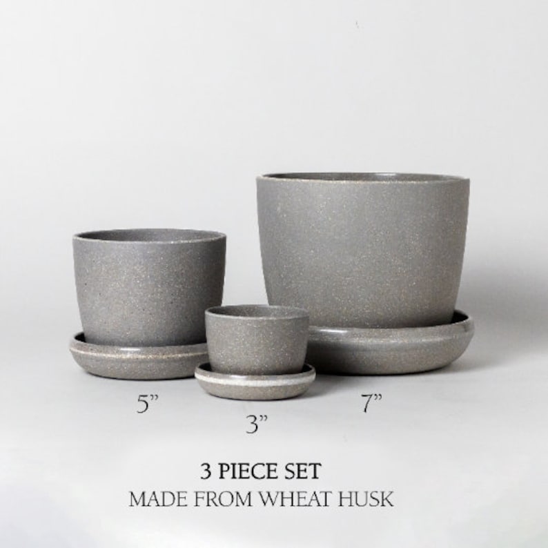 Op de afbeelding: Een set van drie grijze keramische potten met bijpassende schotels. De potten hebben een diameter van 3 inch, 5 inch en 7 inch. De set is gemaakt van tarwevlies.  3 PIECE SET MADE FROM WHEAT HUSK