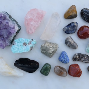 May include: A collection of various crystals and gemstones, including amethyst, rose quartz, clear quartz, tiger's eye, lapis lazuli, red jasper, and more.