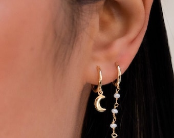 Boucle d’oreille Huggie avec un charme en forme de lune.