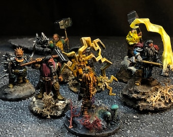 May include: Five miniature figures of dwarves, each with a different weapon and pose. The figures are painted in various shades of brown, gold, and silver. The figures are standing on small bases with a variety of textures, including rocks, moss, and mushrooms.