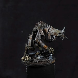 Puede incluir: Una miniatura detallada de una criatura monstruosa con un brazo mecánico y una base esquelética. La criatura está pintada en tonos de marrón, verde y gris, con detalles metálicos.