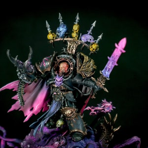 K&ouml;nnte beinhalten: Eine schwarz und gold bemalte Miniaturfigur eines Kriegers mit einem geh&ouml;rnten Helm und einem Schwert. Die Figur steht auf einem Sockel mit lila und schwarzer Farbe. Die Figur tr&auml;gt eine schwarze und goldene R&uuml;stung mit einem lila Umhang.