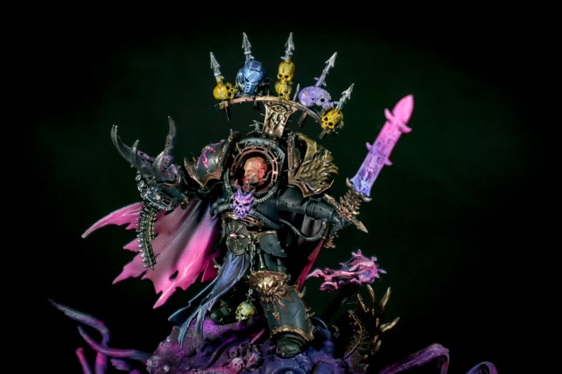 K&ouml;nnte beinhalten: Eine schwarz und gold bemalte Miniaturfigur eines Kriegers mit einem geh&ouml;rnten Helm und einem Schwert. Die Figur steht auf einem Sockel mit lila und schwarzer Farbe. Die Figur tr&auml;gt eine schwarze und goldene R&uuml;stung mit einem lila Umhang.