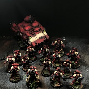 K&ouml;nnte beinhalten: Ein rot-wei&szlig; bemaltes Miniatur-Kriegsfahrzeug mit einer gro&szlig;en Kanone, umgeben von einer Gruppe rot-wei&szlig; bemalter Miniatursoldaten.