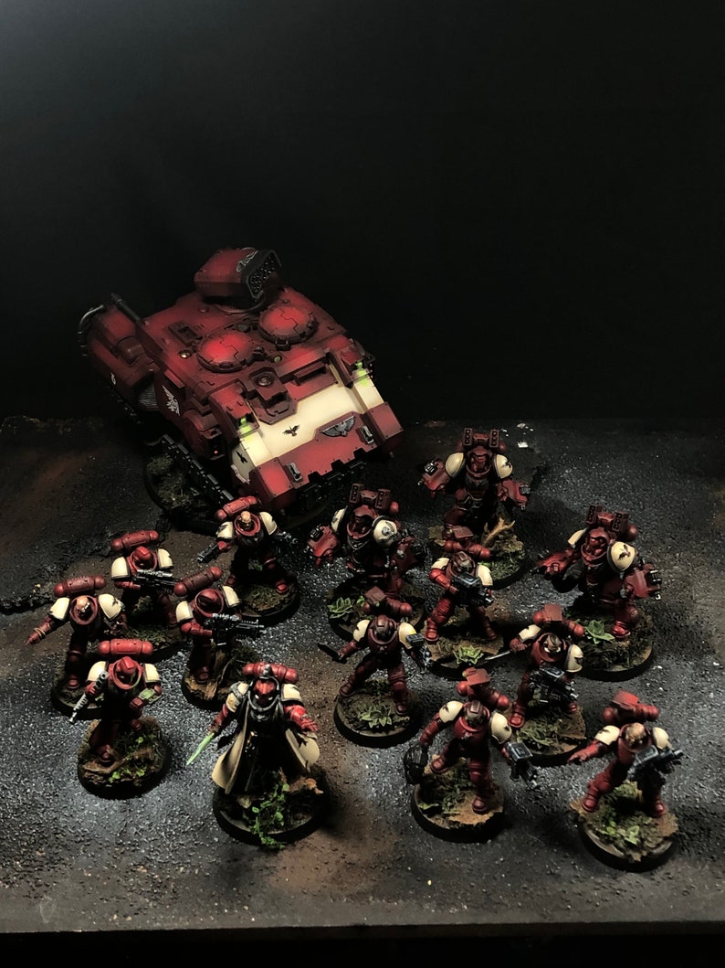 K&ouml;nnte beinhalten: Ein rot-wei&szlig; bemaltes Miniatur-Kriegsfahrzeug mit einer gro&szlig;en Kanone, umgeben von einer Gruppe rot-wei&szlig; bemalter Miniatursoldaten.