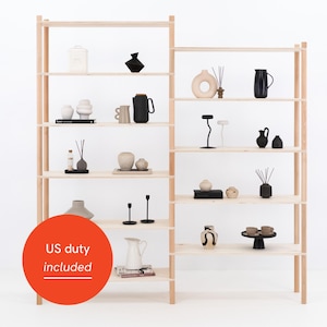 May include: A wooden shelving unit with various decorative items. The shelves display vases, candles, and other home decor in neutral and black tones. The style is minimalist and modern, with a focus on clean lines.