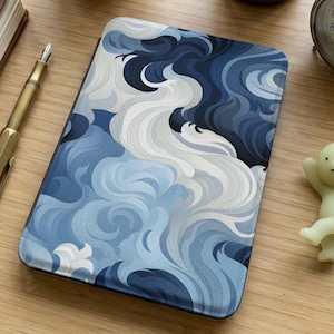 Op de afbeelding: Een rechthoekige hoes met een blauw en wit golfpatroon. Het ontwerp heeft wervelende lijnen in blauwtinten, van donker marineblauw tot licht hemelsblauw en wit. De hoes is waarschijnlijk voor een elektronisch apparaat.